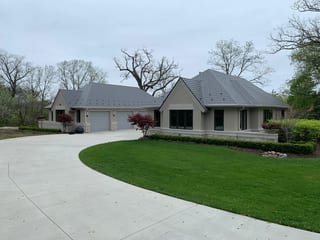 Musket Grey Interlock Slate aluminum roof on a beige one-storey home with a gable roof on a lakeside, Long Grove, Illinois
