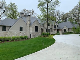 Musket Grey Interlock Slate aluminum roof on a grey two-storey colonial home with dormers in a forested, Long Grove, Illinois
