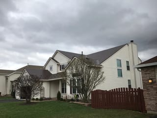 Colonial Brown Interlock Slate aluminum roof on a white Colonial home with dormers and a brown fence, Carol Stream, Illinois