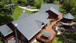 Hunter Green Interlock Shake aluminum roof on a brown one-storey ranch with a green metal roof in a forest, Harvard, Illinois