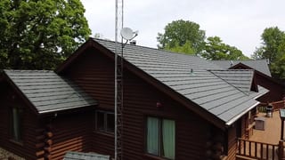 Hunter Green Interlock Shake aluminum roof on a brown log cabin among tall green trees, Harvard, Illinois