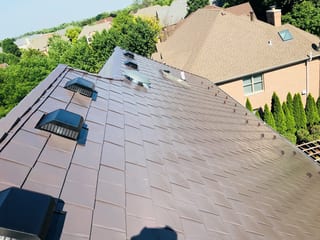 Tudor Brown Interlock Slate aluminum roof on a brown house with a metal roof among tall trees, Roselle, Illinois