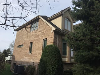 Tudor Brown Interlock Slate aluminum roof on a brown two-storey Tudor home among tall trees, Roselle, Illinois