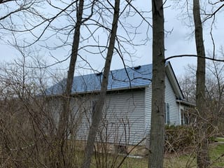 Royal Blue Interlock Slate aluminum roof on a grey home with dormers among bare trees, Woodstock, Illinois