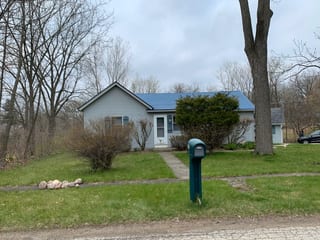 Royal Blue Interlock Slate aluminum roof on a blue single-storey home with a metal roof in a forested, Woodstock, Illinois