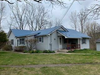 Royal Blue Interlock Slate aluminum roof on a grey ranch home with a metal roof and porch among tall, Woodstock, Illinois