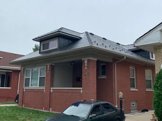 Black Interlock Slate aluminum roof on a red brick home with white trim and a metal roof, Chicago, Illinois