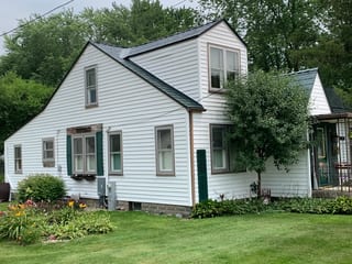 Hunter Green Interlock Slate aluminum roof on a white Cape Cod home with Hunter Green metal roof in a, Braidwood, Illinois