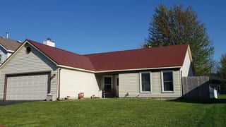 Copper Penny Interlock Cedar Shingle aluminum roof on a cream one-storey home with a metal roof among tall trees, Bolingbrook, Illinois