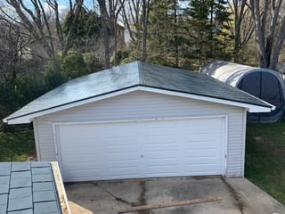 Deep Charcoal Interlock Slate aluminum roof on a white one-storey home with a garage among tall evergreens, Waukegan, Illinois