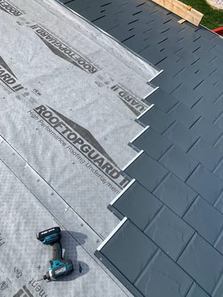 Deep Charcoal Interlock Slate aluminum roof being installed on a grey home with a metal roof in a rural area, Waukegan, Illinois