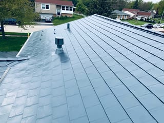 Deep Charcoal Interlock Slate aluminum roof on a tan two-storey home with a red roof and a metal roof in, Elgin, Illinois
