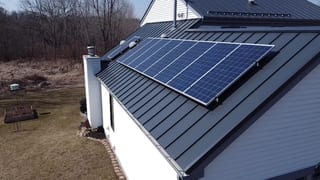 Deep Charcoal Interlock Standing Seam aluminum roof on a white two-storey home with a metal roof among trees, Carpentersville, Illinois