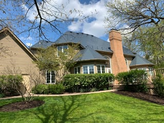 Deep Charcoal Interlock Slate aluminum roof on a tan two-storey colonial home with dormers among tall trees, Crystal Lake, Illinois