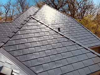 Deep Charcoal Interlock Slate aluminum roof on a brown single-storey home with dormers among tall trees, Crystal Lake, Illinois