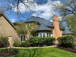 Deep Charcoal Interlock Slate aluminum roof on a tan two-storey Colonial home with dormers among tall pines, Crystal Lake, Illinois