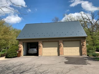 Deep Charcoal Interlock Slate aluminum roof on a tan ranch home with a large garage among tall trees, Crystal Lake, Illinois