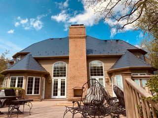 Deep Charcoal Interlock Slate aluminum roof on a tan colonial home with a brown metal roof and chimney, Crystal Lake, Illinois