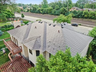 Colonial Brown Interlock Slate aluminum roof on a colonial home with a grey metal roof in a wooded suburban, Calredon Hills, Illinois