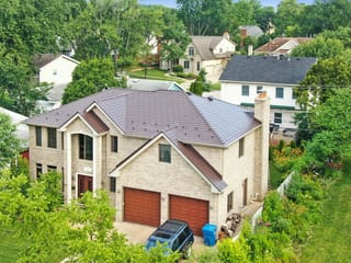 Colonial Brown Interlock Slate aluminum roof on a two-storey colonial home with dormers among lush greenery, Calredon Hills, Illinois