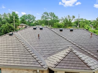 Colonial Brown Interlock Slate aluminum roof on a brown Colonial home with dormers among tall green trees, Calredon Hills, Illinois