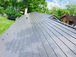 Tudor Brown Interlock Cedar Shingle aluminum roof on a Tudor home with a brown metal roof in a wooded area, Algonquin, Illinois
