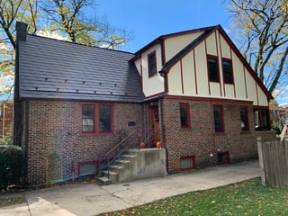 Tudor Brown Interlock Slate aluminum roof on a brown single-family Tudor home with dormers in a forested, Elmhurst, Illinois