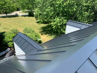 Black Interlock Standing Seam aluminum roof on a modern single-family home in a forested lakeside setting, Lake Forest, Illinois