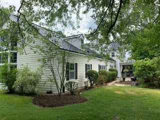 Black Interlock Standing Seam aluminum roof on a white single-family home with dormers among tall pines, Lake Forest, Illinois