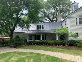 Black Interlock Standing Seam aluminum roof on a white colonial home with dormers among tall trees, Lake Forest, Illinois