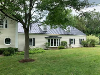 Black Interlock Standing Seam aluminum roof on a white two-storey colonial home with a black metal roof in, Lake Forest, Illinois