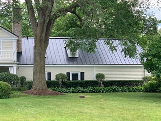 Black Interlock Standing Seam aluminum roof on a cream-coloured colonial home with a metal roof in a, Lake Forest, Illinois