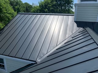 Black Interlock Standing Seam aluminum roof on a black single-family home with a metal roof among tall, Lake Forest, Illinois