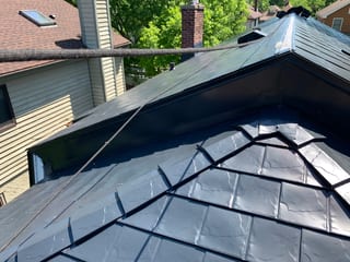 Black Interlock Slate aluminum roof on a black single-family home in a suburban area among lush, Oak Park, Illinois