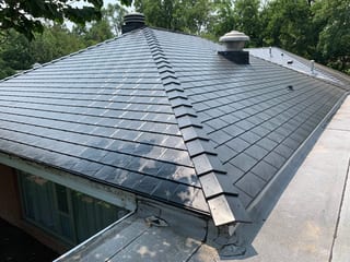 Black Interlock Slate aluminum roof on a brick single-family home with dormers among tall trees, Flossmoor, Illinois