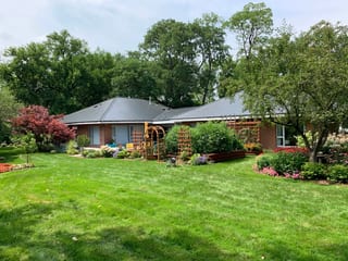 Black Interlock Slate aluminum roof on a red brick ranch home with a grey roof in a lush green, Flossmoor, Illinois