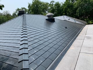 Black Interlock Slate aluminum roof on a black metal roof on a two-storey home among tall trees, Flossmoor, Illinois