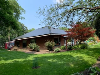 Black Interlock Slate aluminum roof on a brick single-family home with a grey metal roof among, Flossmoor, Illinois