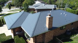 Deep Charcoal Interlock Slate aluminum roof on a red brick home with a metal roof among suburban homes, Westmont, Illinois