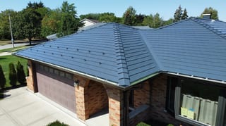 Deep Charcoal Interlock Slate aluminum roof on a brown brick home with a metal roof in a suburban setting, Westmont, Illinois