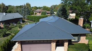 Deep Charcoal Interlock Slate aluminum roof on a brown ranch style home with garage among lush greenery, Westmont, Illinois