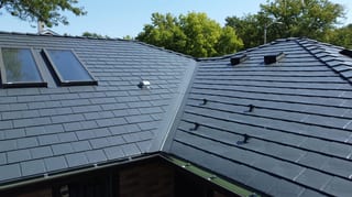 Deep Charcoal Interlock Slate aluminum roof on a dark two-storey home with a metal roof among tall trees, Westmont, Illinois