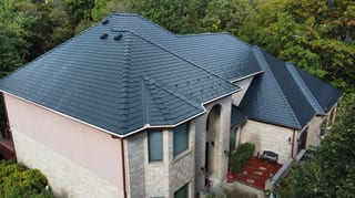 Black Interlock Slate aluminum roof on a beige two-storey home with dormers among tall trees, Lemont, Illinois