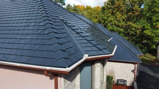 Black Interlock Slate aluminum roof on a white home with a metal roof and a gable among tall trees, Lemont, Illinois