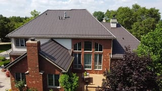Tudor Brown Interlock Tile aluminum roof on a red brick Tudor-style home among trees, Lemont, Illinois