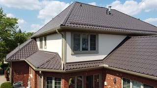 Tudor Brown Interlock Tile aluminum roof on a Tudor-style home with a brown metal roof and white walls, Lemont, Illinois