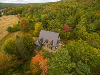 Deep Charcoal Interlock Cedar Shingle aluminum roof on a two-storey cottage with dormers among tall trees, Bar Harbor, Maine
