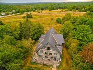 Deep Charcoal Interlock Cedar Shingle aluminum roof on a two-storey Cape Cod home with dormers among tall trees, Bar Harbor, Maine