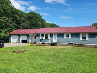 Tile Red Interlock Slate aluminum roof on a red metal roof on a ranch style home surrounded by tall, Lebanon, Maine