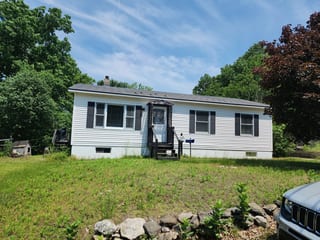 Charcoal Grey Interlock Slate aluminum roof on a white single-storey home with a metal roof in a wooded, Athol, Massachusetts